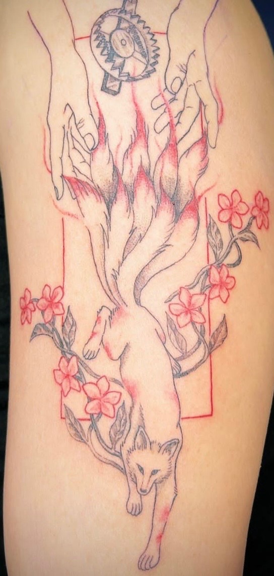 Tattoo of a stylized fox with multiple tails flowing upward into a pair of open hands, surrounded by pink flowers and leaves. Above the hands is a circular mechanical gear. The artwork features fine linework with red and black ink.